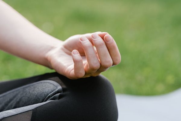Close-up of hands in a meditative gesture on a yoga mat.